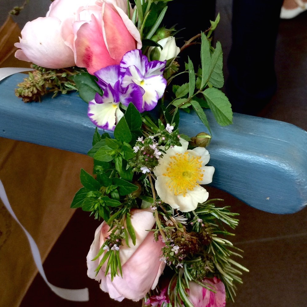 A garland of flowers draped on the handle of a market cart, painted blue.